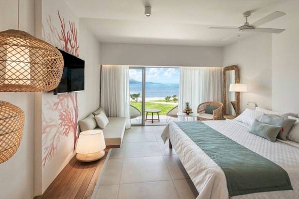 Schlafzimmer im Preskil Island Resort mit Meerblick, Bett, Sofa, Tisch und Balkon.