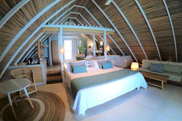 Innenansicht des Schlafzimmers im Preskil Island Resort mit einer weißen Bett, blauen Kissen und einer weißen Decke.