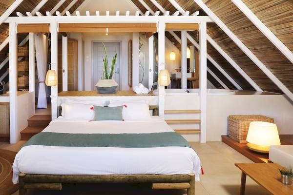 Innenansicht eines Schlafzimmers im Preskil Island Resort mit Bett, Tisch, Stühlen und Dach.