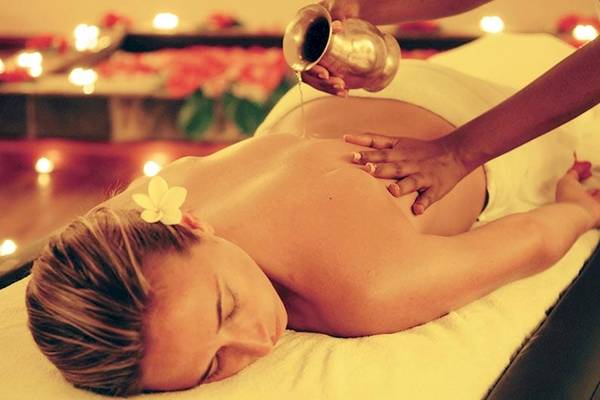 Frau genießt Massage im Preskil Island Resort mit Kerzen und Blumen im Hintergrund