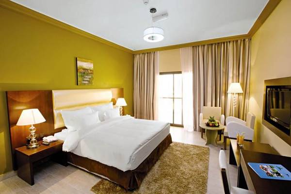 Innenansicht eines Zimmers im BM Beach Resort mit einem großen Bett, Schreibtisch und Fernseher.