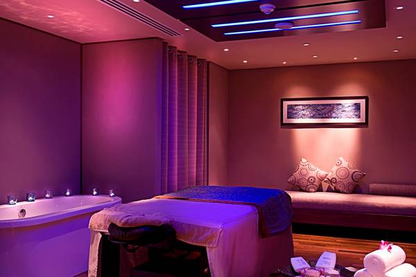 Spa-Behandlungsraum im Grand Millennium Al Wahda Hotel mit violettem Licht und blauer Beleuchtung.