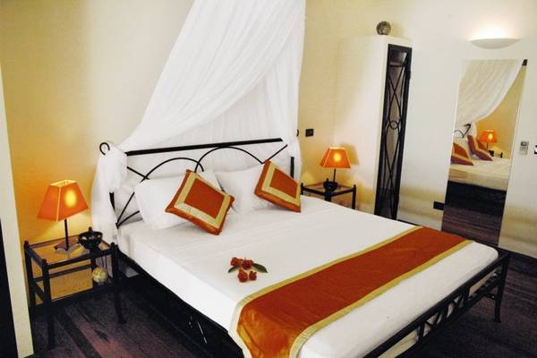 Schlafzimmer im Nakai Maayafushi Resort mit einem Bett, Kissen, Lampen und einem Spiegel.