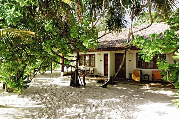 Strandhaus des Nakai Maayafushi Resorts, umgeben von Bäumen und Sand.