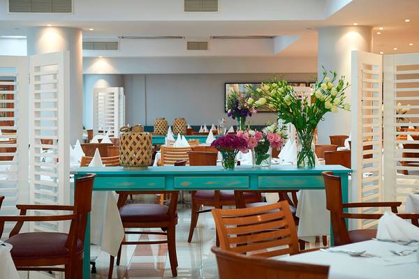 Innenansicht des Restaurants im Louis Ledra Beach Hotel mit blauem Tisch und Blumenvasen.