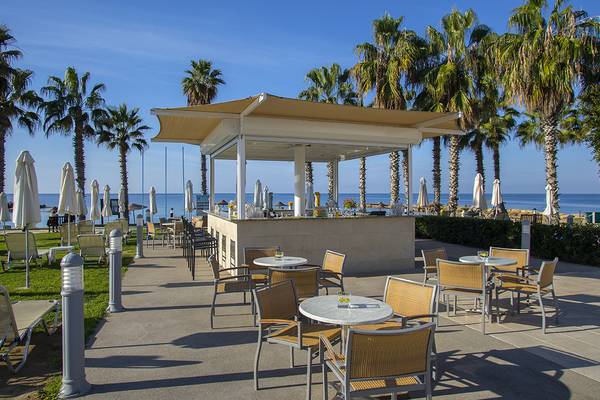 Außenbereich des Louis Ledra Beach Hotels mit Strandbar und Sonnenliegen.