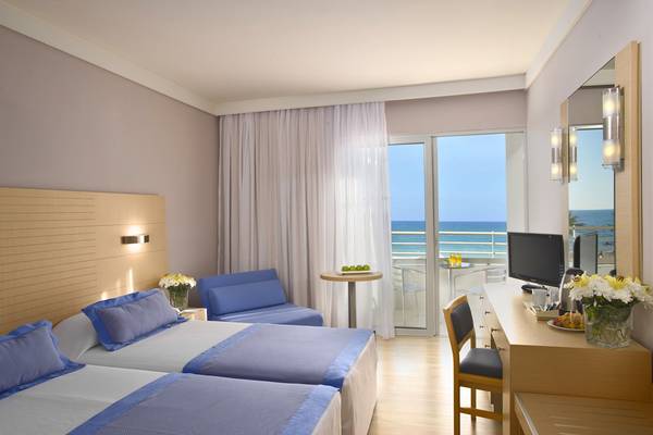 Doppelzimmer mit Meerblick im Hotel Louis Ledra Beach mit zwei Betten, Schreibtisch, Fernseher, und einem Balkon.