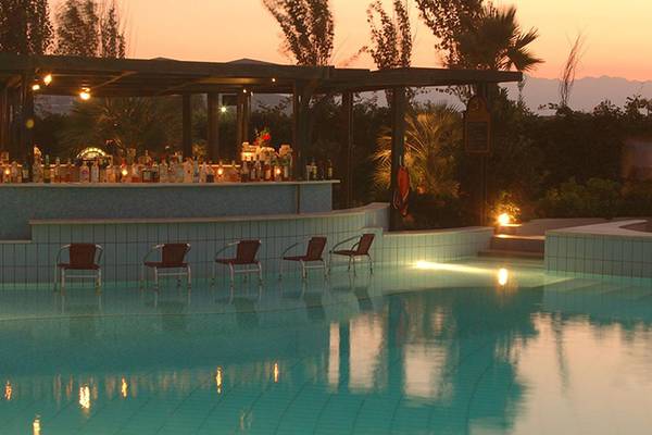 Minos Mare Hotel Poolbar bei Sonnenuntergang mit leeren Stühlen und gefüllten Bar.