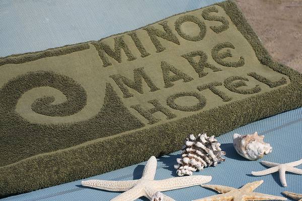 Ein Minos Mare Hotel Handtuch mit Meeresmuscheln und Seesternen auf einem Liegestuhl