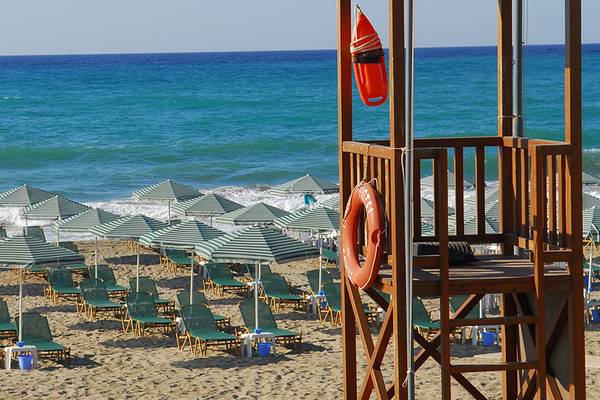 Eine Strandszene mit vielen Sonnenliegen und Sonnenschirmen vor dem Hintergrund eines blauen Ozeans.