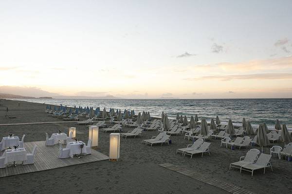 Sonnenuntergang am Strand des Minos Mare Hotels mit vielen Sonnenliegen und Schirmen.