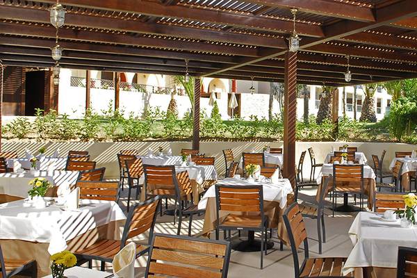 Außenterrasse des Minos Mare Hotels mit gedeckten Esstischen und Holzmöbeln.