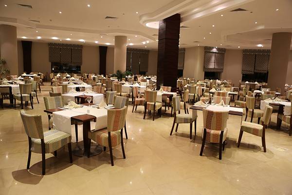 Innenbereich des Rixos Sharm El Sheikh Restaurants mit vielen gedeckten Tischen und Stühlen.