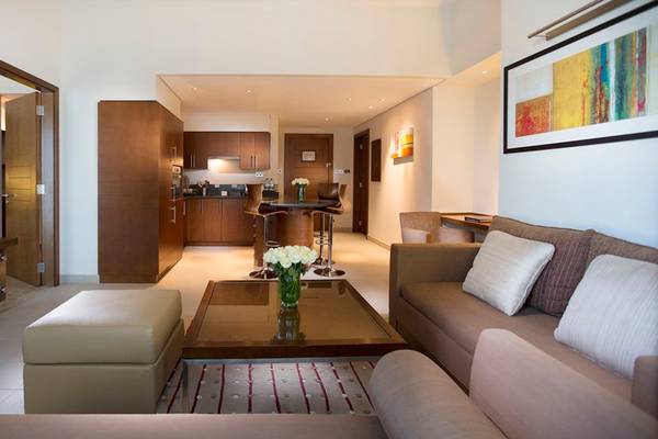 Wohnzimmer im Grand Millennium Al Wahda Hotel mit Couch, Couchtisch und Essbereich.