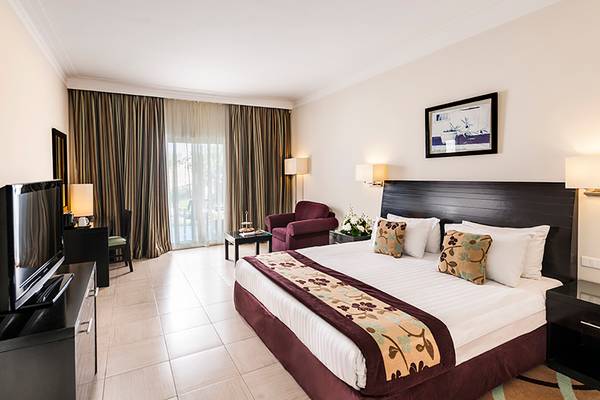 Hotelzimmer im Rixos Sharm El Sheikh mit einem Bett, Fernseher, Sessel und Fenstern.