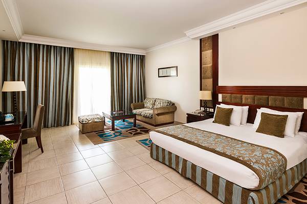 Hotelzimmer im Rixos Sharm El Sheikh mit Doppelbett, Sofa, Tisch und Fenstern.