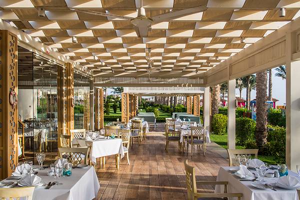 Restaurantterrasse des Rixos Sharm El Sheikh mit gedeckten Tischen und Deckenventilatoren