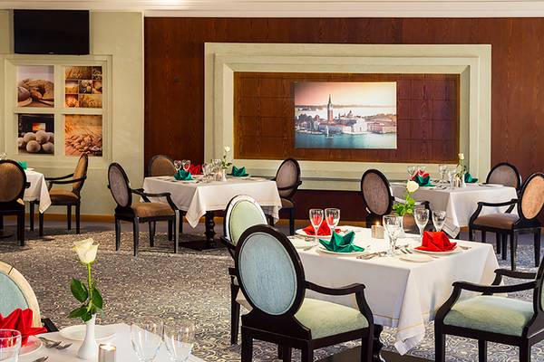 Innenansicht des Restaurants im Rixos Sharm El Sheikh Hotel mit dekorierten Tischen und Panoramabild.