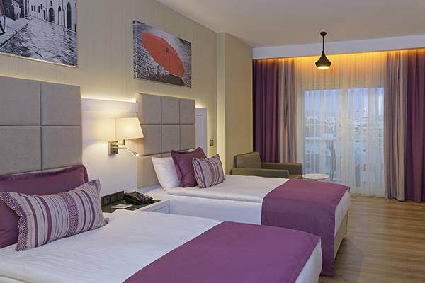 Doppelzimmer im Asia Beach Resort & Spa mit zwei Betten, Fernseher, Schreibtisch und Obstplatte.