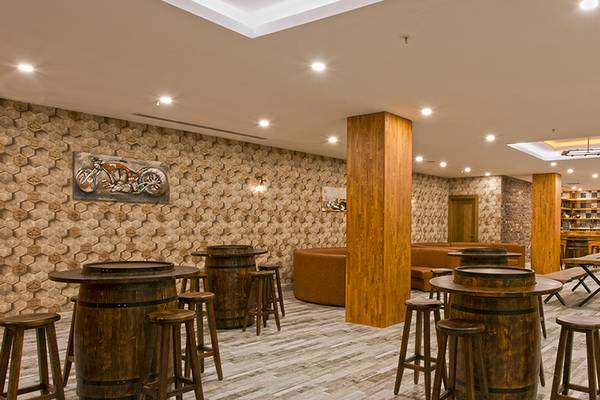Innenansicht der Bar im Asia Beach Resort & Spa Hotel mit Holztischen, Stühlen und einer Wanddekoration.