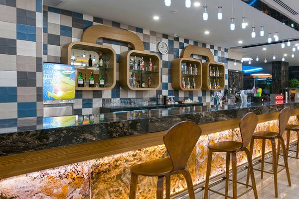 Innenansicht der Bar im Asia Beach Resort & Spa mit Holzstühlen und Marmortheke.