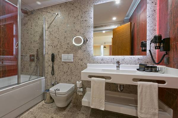Badezimmer im Asia Beach Resort & Spa mit roten Wänden, Badewanne, Dusche, Toilette, Waschbecken und Spiegel