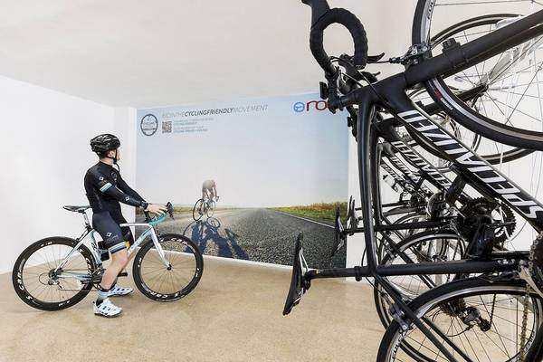 Im Alua Leo Hotel steht ein Fahrrad neben einer Wand mit einem großen Bild von Radfahrern.
