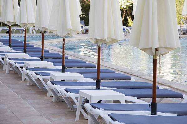 Reihe von weißen und blauen Liegestühlen am Pool des Alua Leo Hotels