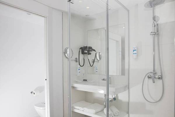 Badezimmer im Alua Leo Hotel mit Glasdusche, Waschbecken und Toilette.