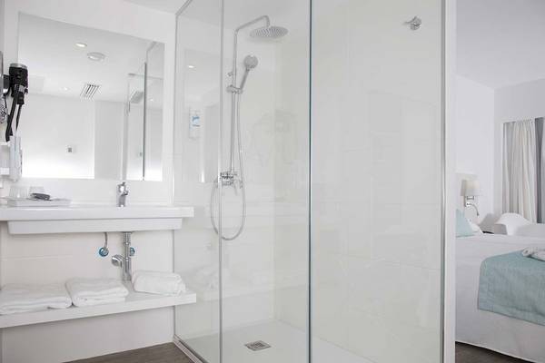 Badezimmer im Alua Leo Hotel mit Duschkabine, Waschbecken und Bett