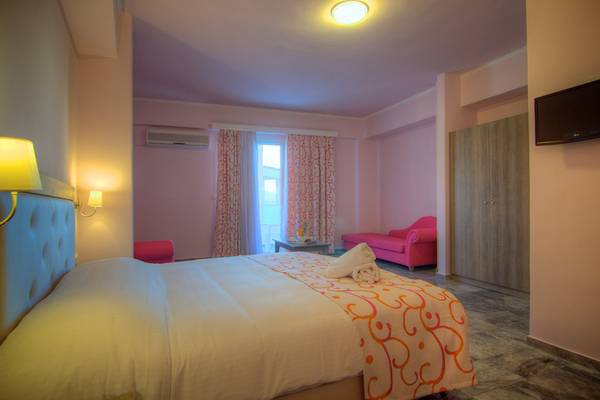 Hotelzimmer im Solimar Dias mit einem Bett, zwei pinken Sesseln, einem Fenster mit Vorhängen und einer Lampe.