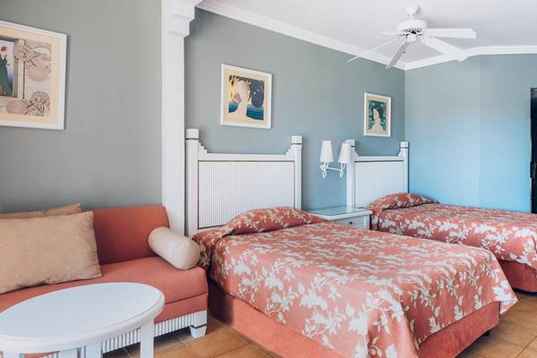 Doppelzimmer im Iberostar Laguna Azul Hotel mit zwei Betten, Couch, Nachttisch und Deckenventilator.