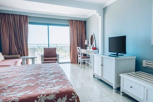 Hotelzimmer im Iberostar Laguna Azul mit Bett, Fernseher, Schreibtisch und Balkon.