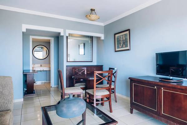 Wohnzimmer des Iberostar Laguna Azul Hotels mit Fernseher, Esstisch und Stühlen.