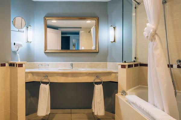 Badezimmer im Iberostar Laguna Azul Hotel mit Spiegel, Waschbecken, Handtüchern und Badewanne.