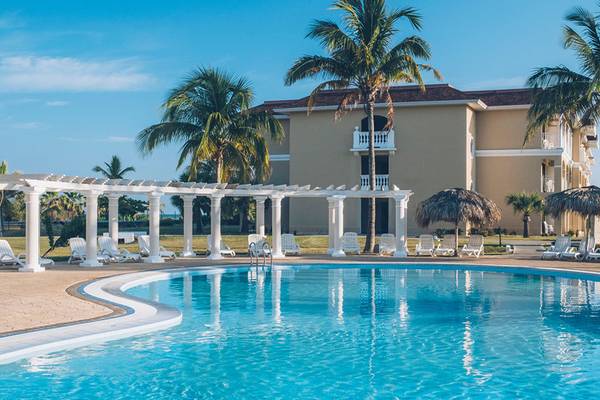 Außenpool und Loungebereich des Iberostar Laguna Azul Hotels mit weißen Liegestühlen und Palmen