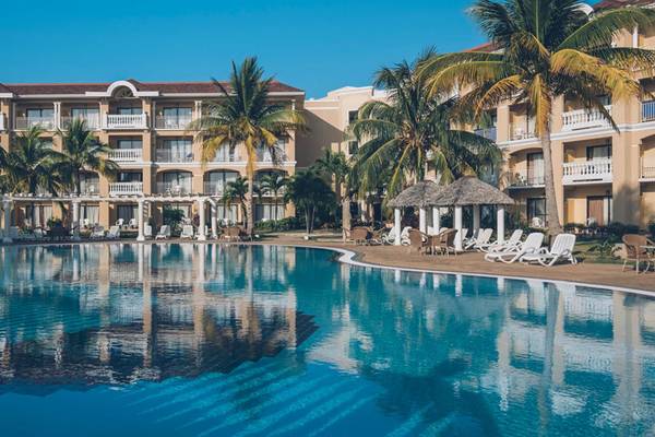 Ein großer Swimmingpool vor dem Iberostar Laguna Azul Hotel mit Lounge-Stühlen und Palmen.