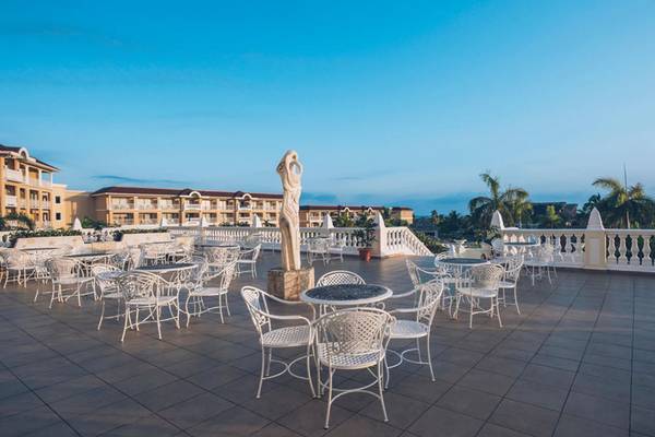 Außenterrasse des Iberostar Laguna Azul Hotels mit weißen Tischen und Stühlen.
