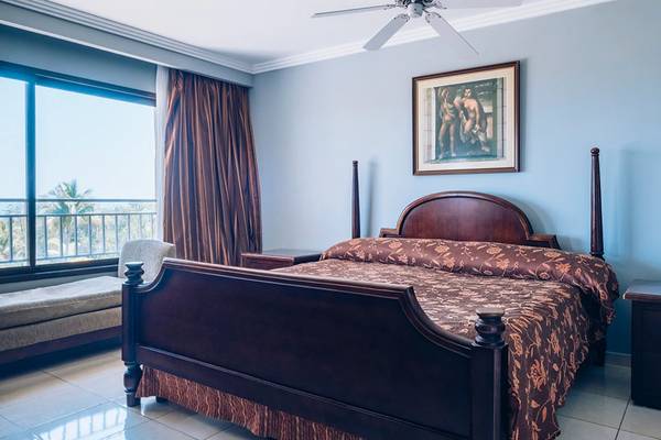 Schlafzimmer im Iberostar Laguna Azul Hotel mit Bett, Nachttischen und Gemälde an der Wand.