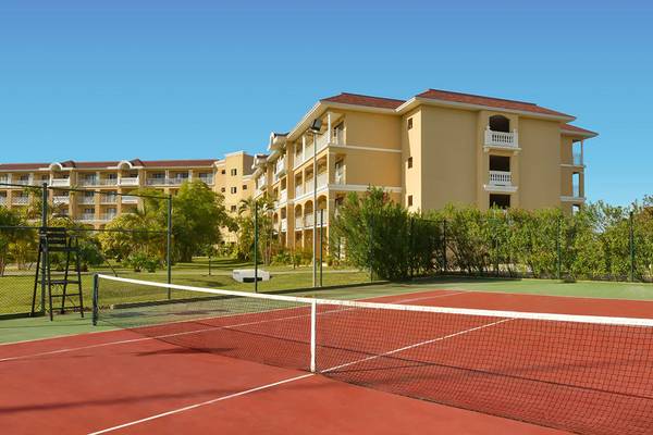 Tennisplatz vor dem Iberostar Laguna Azul Hotel mit gelben Gebäuden und blauem Himmel.