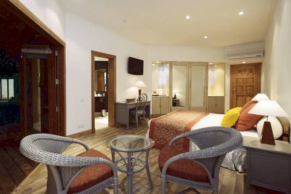 Hotelzimmer im Adaaran Club Rannalhi mit zwei Sessel, Schreibtisch, Bett und Fernseher.