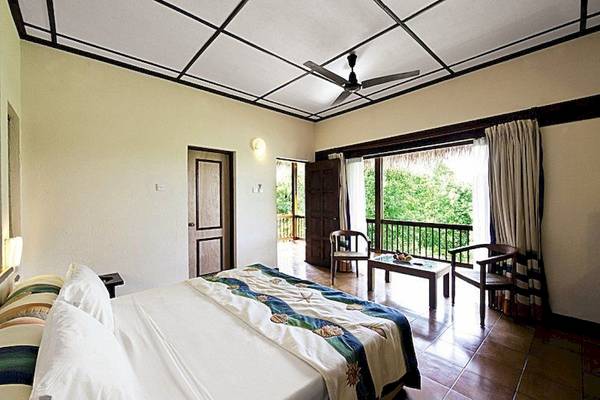 Schlafzimmer im Adaaran Club Rannalhi mit großem Bett, Fenstern und Balkon.