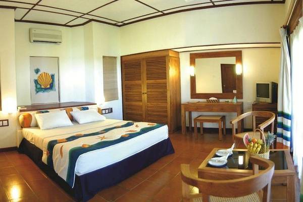 Ein Schlafzimmer im Adaaran Club Rannalhi Hotel mit einem Bett, Möbeln und einer Klimaanlage.