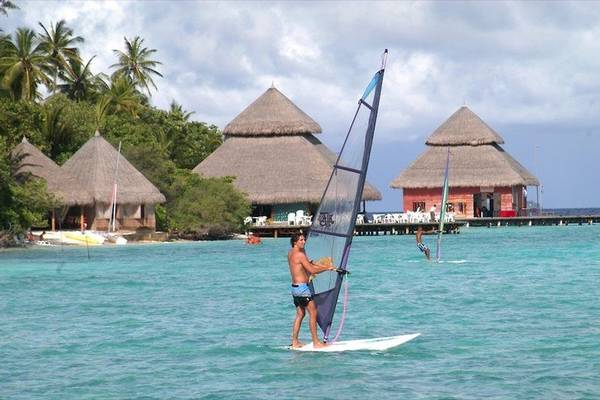 Windsurfer vor den Gebäuden des Adaaran Club Rannalhi Hotels im Wasser