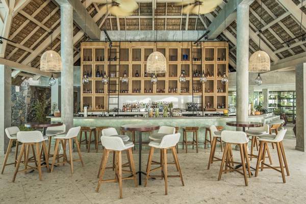 Innenansicht der Bar im Sugar Beach Mauritius Hotel mit Holzstühlen und Tischen.
