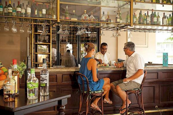 Ein Hotelgast unterhält sich an der Bar des Sugar Beach Mauritius Hotels mit dem Barkeeper.