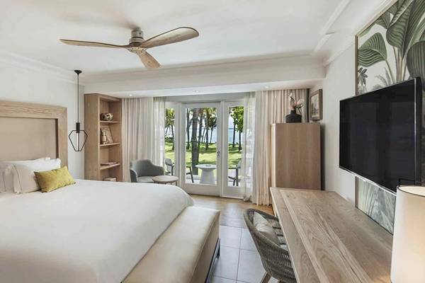 Innenansicht eines Schlafzimmers im Sugar Beach Mauritius Hotel mit Bett, Fernseher und Aussicht auf den Ozean.