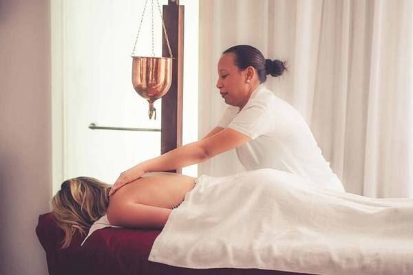 Massagebehandlung im Sugar Beach Mauritius Hotel mit Therapeutin, die Rückenmassage gibt.