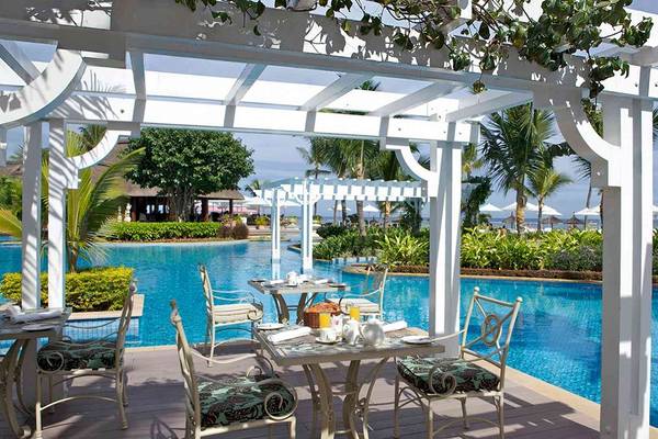 Poolseite der Terrasse im Sugar Beach Mauritius Hotel mit weißen Möbeln und Blick auf das Meer