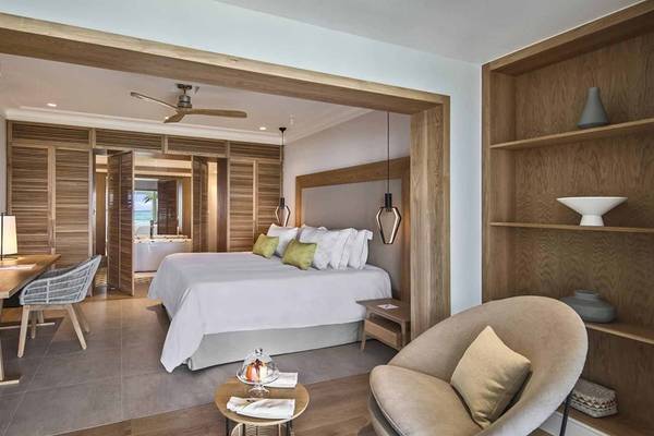 Luxuriöses Zimmer im Sugar Beach Mauritius Hotel mit Bett, Schreibtisch und Wohnbereich.